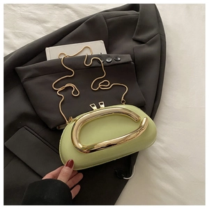 Détail d'un sac à main en cuir vert clair avec poignée dorée et chaîne serpent