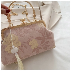 Dettaglio borsa a fiori rosa con manico dorato, catena e nappa bianca decorativa
