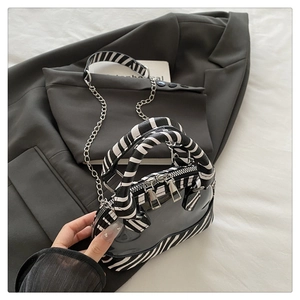 Détail du sac Boston en PVC imprimé zèbre avec double zip argenté et bandoulière chaîne