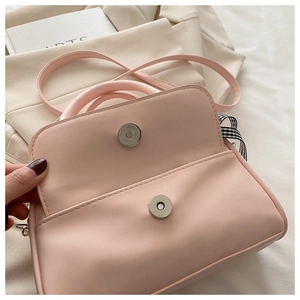 Detail of light pink shell bag with silver magnetic clasp and plaid bow ribbon strap