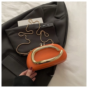 Détail du sac en cuir verni orange vif avec grande poignée en C dorée et chaîne