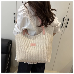 Close-up of beige woven tote bag with pink leather strap and fashion leather patch