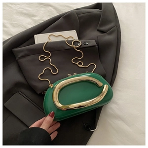 Détail du sac à main vert brillant avec poignée dorée et bandoulière chaîne serpent