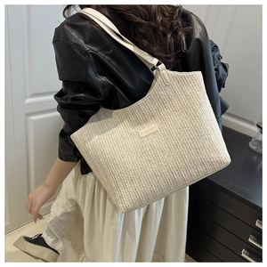 Dettaglio della borsa tote intrecciata color crema con etichetta e trama materica