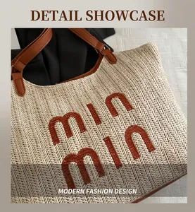 Detail of straw woven tote with brown leather handles and brand logo embroidery