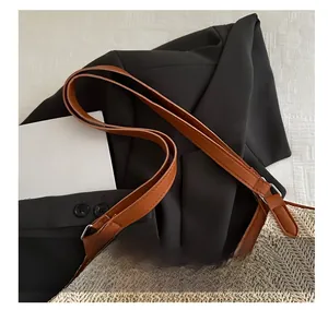 Detailed view of woven straw bag texture and brown leather strap with metal buckle