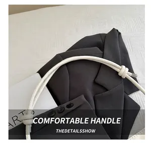 Detail of white leather tote handle with cylindrical stitching and decorative knot