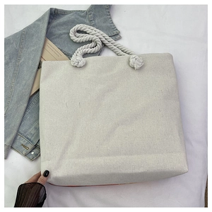 Détail d'un grand sac cabas en toile beige avec de larges anses en corde blanche et texture