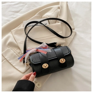 Close-up of black woven cylinder bag with gold twist locks and lace bow detail