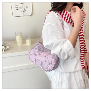 Detail of light pink shoulder bag with grey bamboo leaf print worn by a model