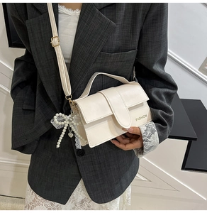 Detail of cream white PU leather crossbody bag with pearl lace bow pendant and top handle