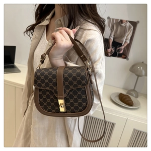 Detail of vintage pattern crossbody bag with gold clasp and leather trim on a beige shirt