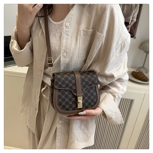 Classic saddle bag with retro monogram pattern and gold buckle on a brown leather strap
