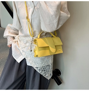Detail of yellow crossbody bag with pearl heart charm and white shirt outfit style
