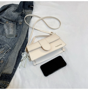 Detail of off-white faux leather shoulder bag with gold lettering and pearl charm