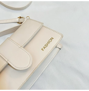 Detailed close-up of cream white PU leather bag with gold Fashion text and metal buckle