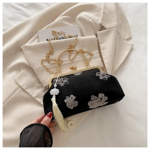 Dettaglio del ricamo floreale e del manico dorato su una borsa da sera vintage in velluto