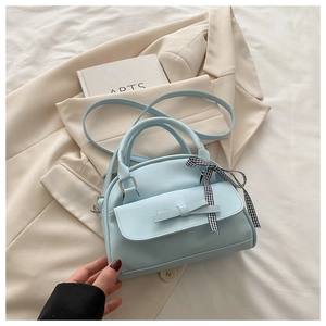 Detailed view of light blue shell bag with ribbon bow and elegant checkered scarf decor