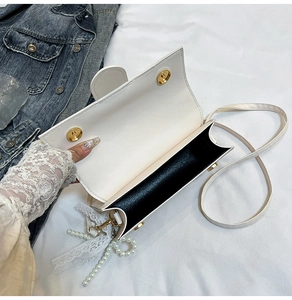 Detail of white PU leather flap bag featuring pearl lace pendant and magnetic buckles