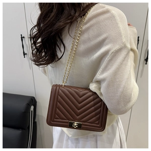 Vue détaillée du sac bandoulière marron foncé matelassé avec chaîne dorée sur mannequin