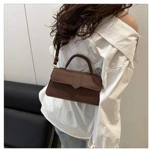 Close-up of a brown vintage matte leather handbag styled with a white outfit for women