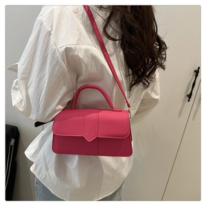 Détail d'un sac à main rose vif minimaliste avec une chemise blanche et un jean bleu