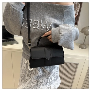 Chic black matte PU leather handbag with top handle and slim shoulder strap on model