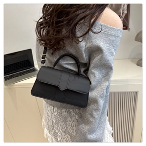 Detail shot of black leather handbag with golden hardware worn in an office setting