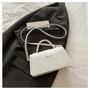 Close-up of minimalist white PU leather handbag on a grey blazer in a stylish setting