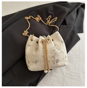 Détail de broderie florale sur sac seau crème avec cordon perlé et chaîne dorée