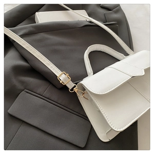 Detail view of white PU leather flap handbag with gold metal hardware and adjustable strap