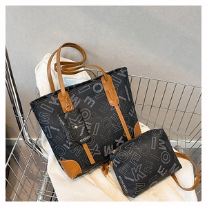 Detail of vintage square tote bag with monogram print and brown leather trim in a cart