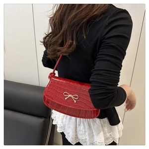 Detail of red crocodile texture handbag with a golden metal bow and glossy finish