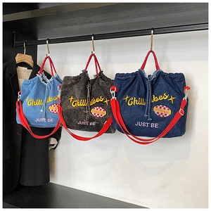 Detail showing denim tote bags in three colors with embroidery and red straps