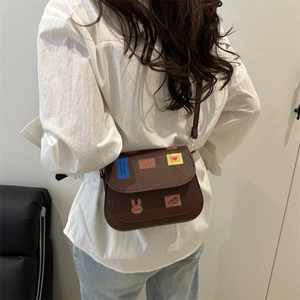 Brown leather square crossbody bag with colorful patches shown on a model