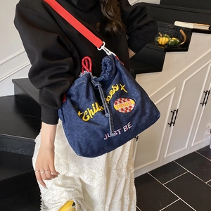 Dunkelblaue Denim-Beuteltasche mit Childhood-Stickerei und leuchtend rotem Schultergurt