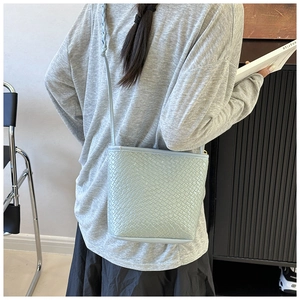 Detail showing mint green woven leather bucket bag with slim shoulder strap texture
