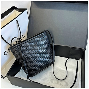 Detail of black woven leather bucket bag featuring a classic intrecciato pattern finish