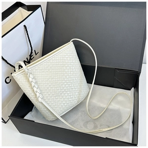 Detailed view of white woven bucket bag with braided strap inside a gift box