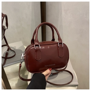 Détail d'un sac bowling rouge foncé brillant avec poignées rondes et logo élégant