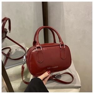 Détail du sac à main en cuir verni rouge avec lettrage mode et fermeture éclair argentée