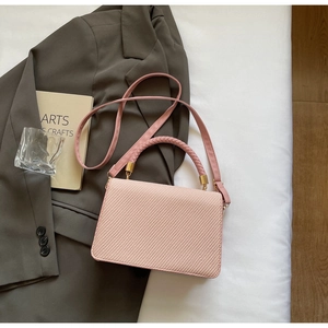 Détail d'un sac bandoulière rose tissé avec garnitures dorées et poignée supérieure