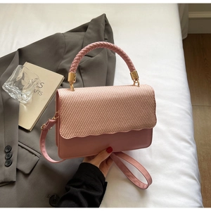 Détail d'un sac rose avec rabat à texture tissée, bords festonnés et finitions dorées