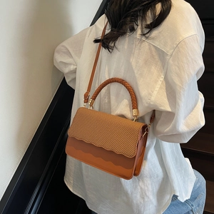 Sac bandoulière marron en patchwork avec rabat tissé et bordure ondulée sur un modèle