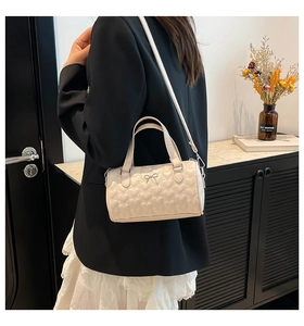 Detalle de bolso boston beige con acolchado de corazón y lazo en modelo para diario