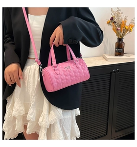 Detalle del bolso cilíndrico rosa con pespuntes de corazón y adorno de lazo metálico