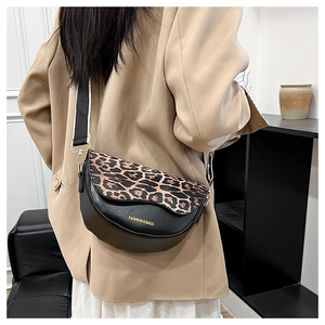 Detail of vintage saddle bag with leopard print flap and wide striped strap on model