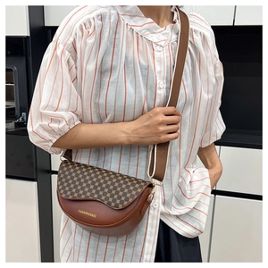 Detail view of a brown saddle bag with geometric patterns and broad fabric strap