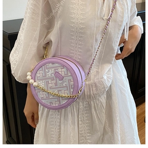 Detailed embroidery and pearl chain on a lilac circular crossbody bag with floral patterns