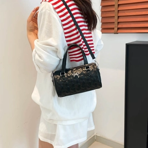 Bolso cilíndrico negro acolchado de corazones con lazo plateado y correa ajustable